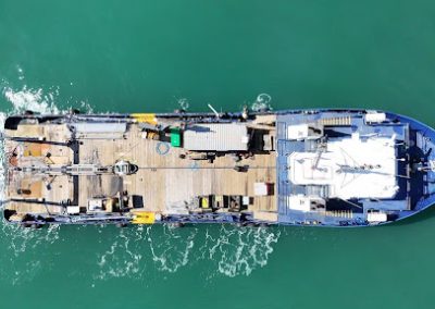 Profile view of the R/V Peter M Mahoney vessel floating at sea, showcasing its deck space and crane equipment.